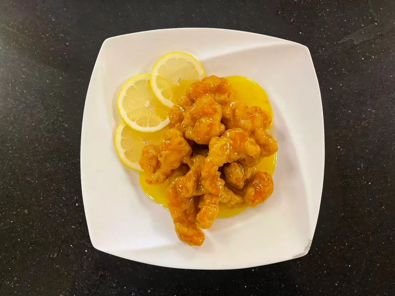 Crispy lemon glazed meat served with fresh lemon slices